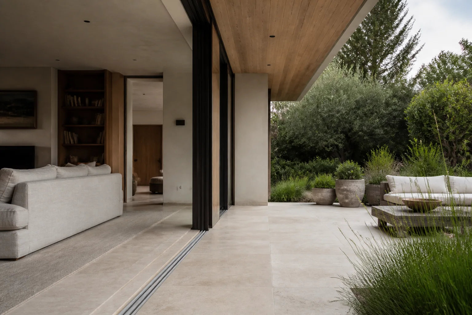 A flush limestone threshold joining the living room and shaded garden terrace